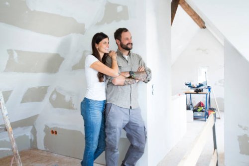 smiling couple in attic to be renovated looking out of window - home decoration stock pictures, royalty-free photos & images