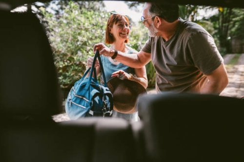 smiling couple packing bags in their car after a weekend away - travel stock pictures, royalty-free photos & images