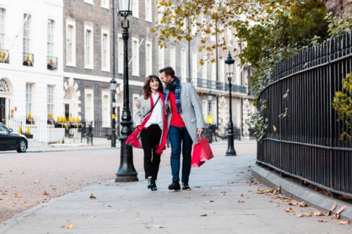 smiling couple walking along the street with shopping bags - fashion stock pictures, royalty-free photos & images