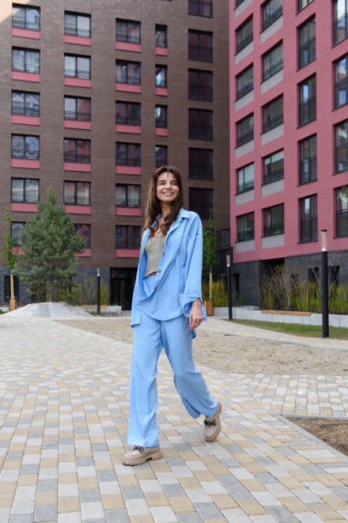 smiling fashionable woman in a blue suit posing in a new collection of summer clothes on a city street - fashion stock pictures, royalty-free photos & images
