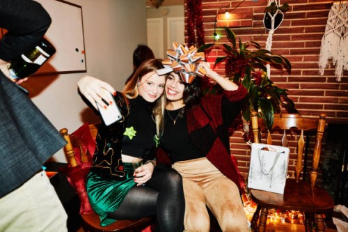 smiling female friends posing for selfie with bow over their heads during holiday party in home - home decoration stock pictures, royalty-free photos & images