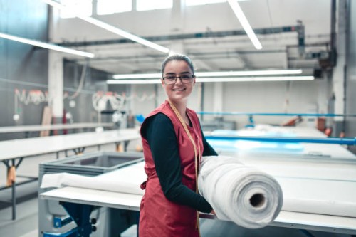 smiling female textile worker carrying heavy rolled materials for printing roller machine - fashion stock pictures, royalty-free photos & images