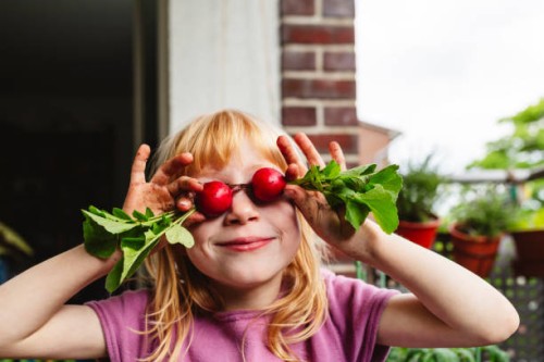 smiling girl covering eyes with fresh radish on balcony - food stock pictures, royalty-free photos & images