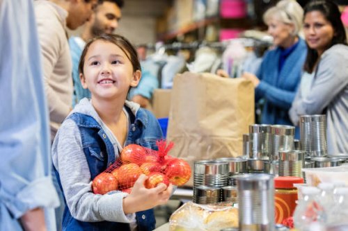 smiling little girl donates apples to food bank - food stock pictures, royalty-free photos & images