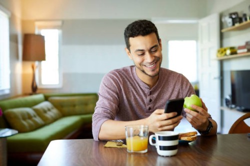 smiling man using mobile phone while holding apple - food stock pictures, royalty-free photos & images