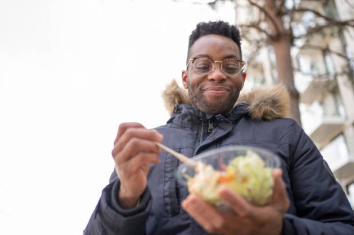 smiling man with eyeglasses having salad during winter - junk food stock pictures, royalty-free photos & images