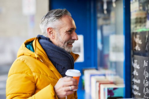 smiling mature man at a stall with takeaway coffee - junk food stock pictures, royalty-free photos & images