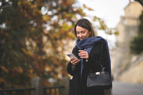 smiling mid adult woman online messaging outdoors. - fashion stock pictures, royalty-free photos & images