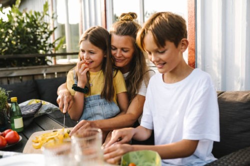 smiling mother cutting vegetable on table in balcony - food stock pictures, royalty-free photos & images