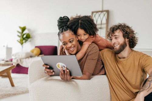 smiling parents and daughter at home watching online movie together - home decoration stock pictures, royalty-free photos & images