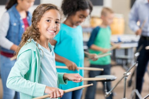 smiling schoolgirl plays drums during percussion class - concert stock pictures, royalty-free photos & images