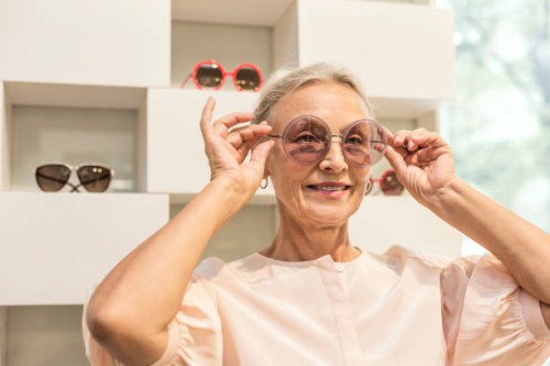 smiling senior woman trying on sunglasses in a boutique - fashion stock pictures, royalty-free photos & images