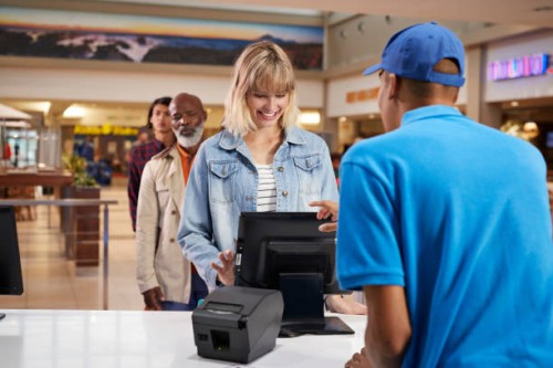 smiling woman buying tickets at counter in theater - junk food stock pictures, royalty-free photos & images