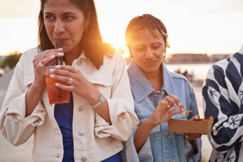 smiling woman drinking juice by friends - junk food stock pictures, royalty-free photos & images
