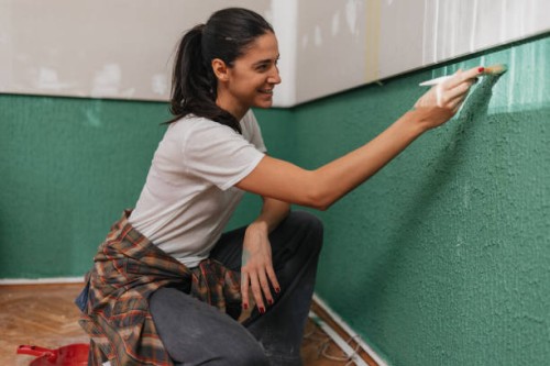 smiling woman finishing wall painting task - home decoration stock pictures, royalty-free photos & images