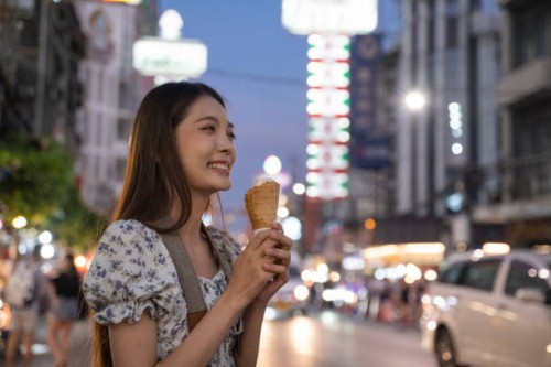 smiling woman holding ice cream on street food in thailand in summer. - junk food stock pictures, royalty-free photos & images