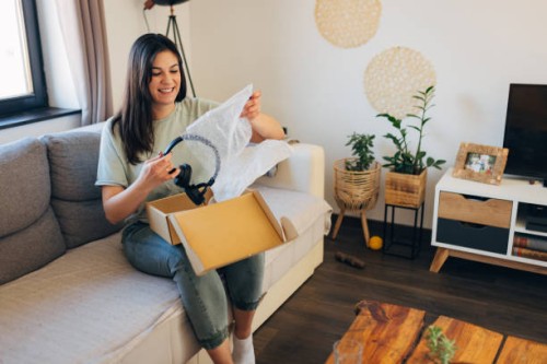 smiling woman opening cardboard package, receiving online store delivery at home - home decoration stock pictures, royalty-free photos & images