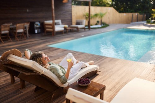 smiling woman relaxing on a lounge chair by the pool. - garden decoration photos et images de collection