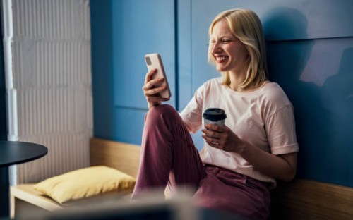 smiling woman sitting in a cafe and looking at mobile phone - junk food stock pictures, royalty-free photos & images