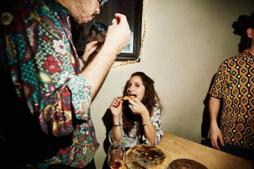 smiling woman taking bite of pizza during party with friends in night club - food stock pictures, royalty-free photos & images
