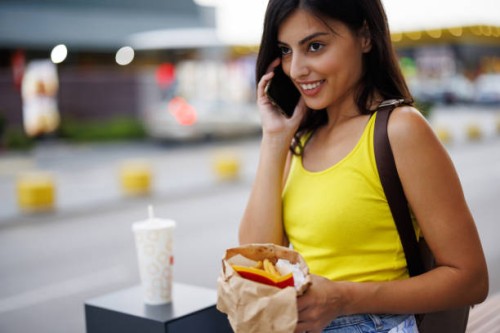 smiling woman talking on mobile phone in the city - junk food stock pictures, royalty-free photos & images
