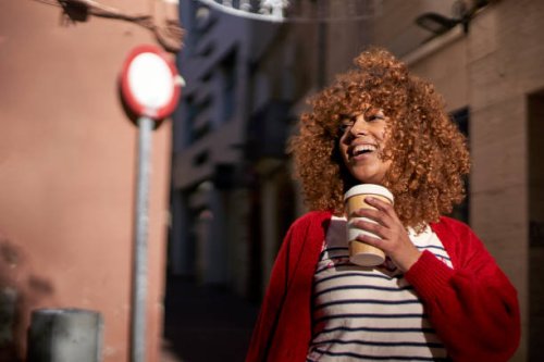 smiling woman with disposable coffee cup looking away while standing outdoors - junk food stock pictures, royalty-free photos & images
