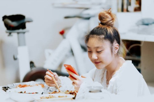 smiling young asian woman enjoying chinese food in bedroom - junk food stock pictures, royalty-free photos & images