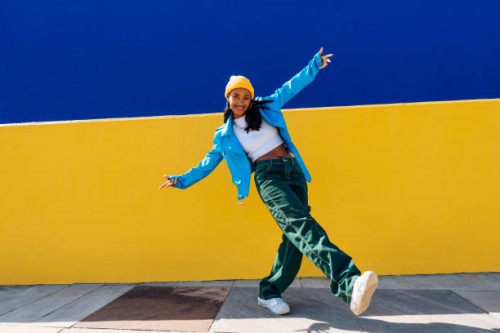 smiling young dancer dancing with arms outstretched on footpath - fashion stock pictures, royalty-free photos & images