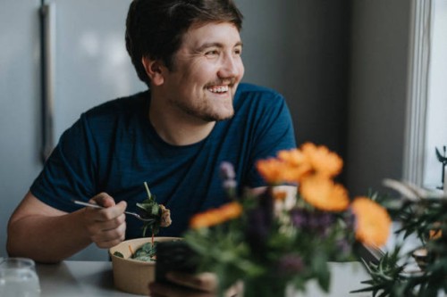 smiling young man eating meal at table - food stock pictures, royalty-free photos & images