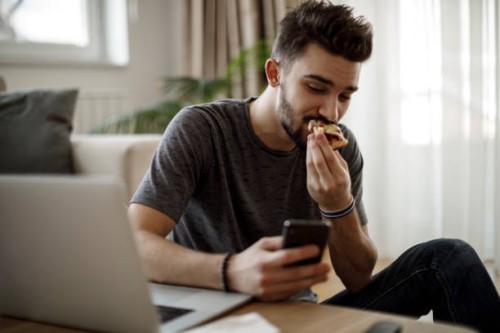 smiling young man using social media at home - junk food stock pictures, royalty-free photos & images