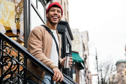 smiling young man walking down stairs in city - fashion stock pictures, royalty-free photos & images