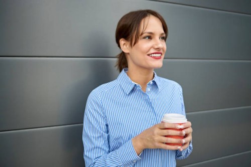 smiling young white caucasian woman on the move drinking coffee from disposable cup. - junk food stock pictures, royalty-free photos & images