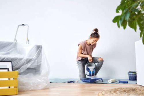 smiling young woman pouring paint in paint tray while kneeling at home - home decoration stock pictures, royalty-free photos & images