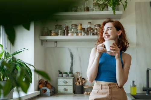 smiling young woman standing with coffee cup at home - coffee stock pictures, royalty-free photos & images