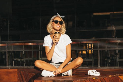 smiling young woman with cell phone and takeaway drink at the cafe - junk food stock pictures, royalty-free photos & images