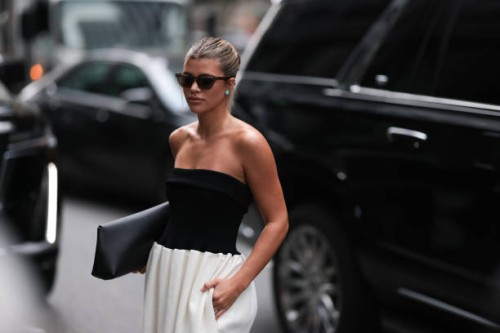 Sofia Richie is seen outside Proenza Schouler show wearing brown Saint Laurent sunnies, Tiffany blue circle earrings, black shoulder free top, white...