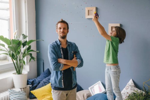 son blowing confetti over proud father holding hammer at home - home decoration stock pictures, royalty-free photos & images