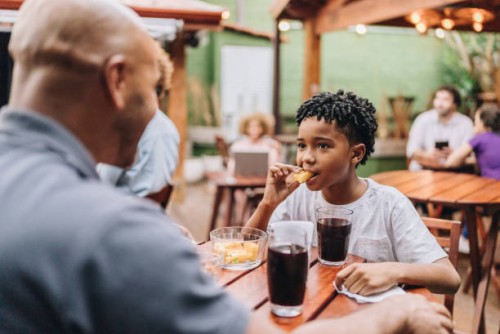 son eating and talking with father at restaurant - junk food stock pictures, royalty-free photos & images