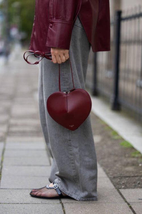 Sonia Lyson wears ballerinas and burgundy heart shaped bag Alaia, grey wide leg jeans Levis, leather shirt Gant on the way to Gmbh during the Berlin...