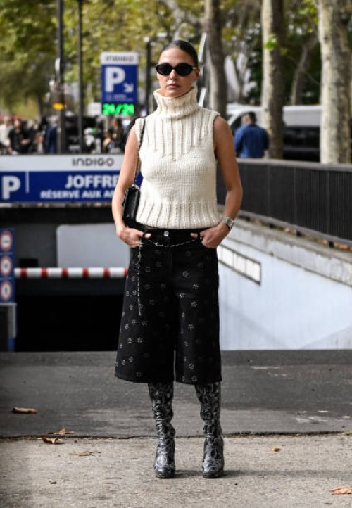 Sophia Roe is seen wearing a cream sleeveless sweater, black and white print shorts, skinny belt, black and gray Chanel boots and black...