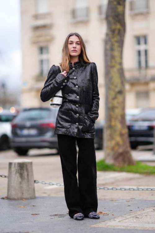 Sophia Roe wears a black shiny glitter jacket, a black and white striped bag, black flared corduroy pants , outside Chanel, during the Womenswear...