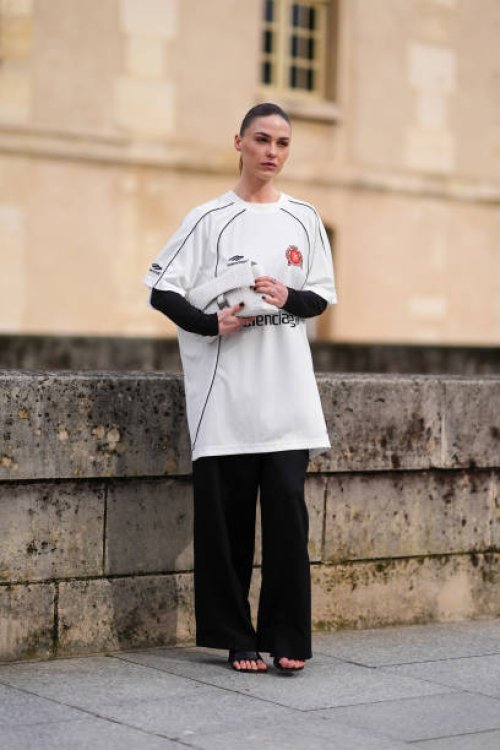 Sophia Roe wears a white Balenciaga top designed as a soccer / football top, black wide-leg pants, black leather high heels shoes, a white Balenciaga...