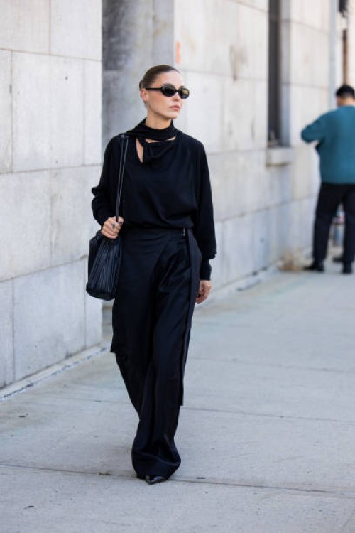 Sophia Roe wears navy wide leg pants, shirt, bag outside Cos during New York Fashion Week on September 10, 2024 in New York City.