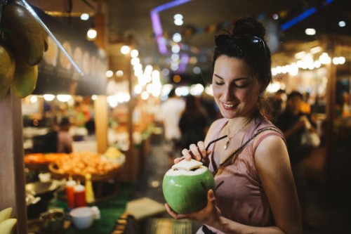souriante jeune femme ayant une eau délicieuse et fraîche de noix de coco sur le pouce - food photos et images de collection