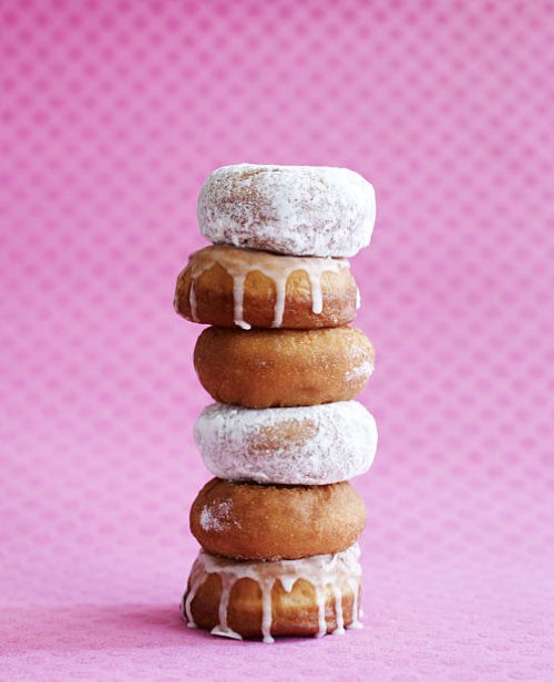 stack of donuts on pink background - junk food stock pictures, royalty-free photos & images