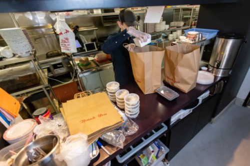 staff in restaurant kitchen preparing and packaging food for delivery during covid-19 pandemic - junk food stock pictures, royalty-free photos & images
