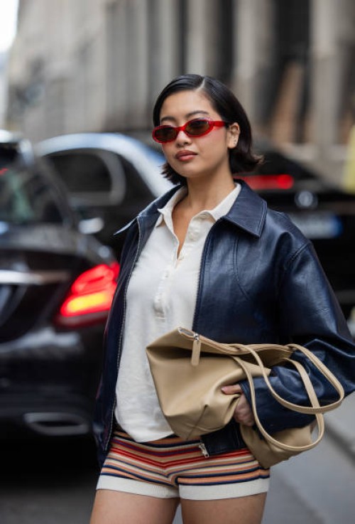 Stephanie Hui wears black leather jacket, brown bag, striped shorts, white polo outside Lacoste during Womenswear Spring/Summer 2025 as part of Paris...