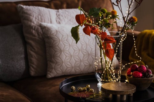 still life of christmas home decor with vase, green and orange flowers, lights, christmas ornaments - home decoration stock pictures, royalty-free photos & images