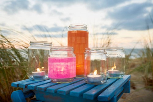 still life of lanterns and jars with tea lights for party decoration against marram grass, sea and sky - home decoration stock pictures, royalty-free photos & images