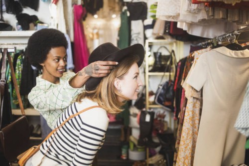 store owner trying hat on female customer in boutique - fashion stock pictures, royalty-free photos & images